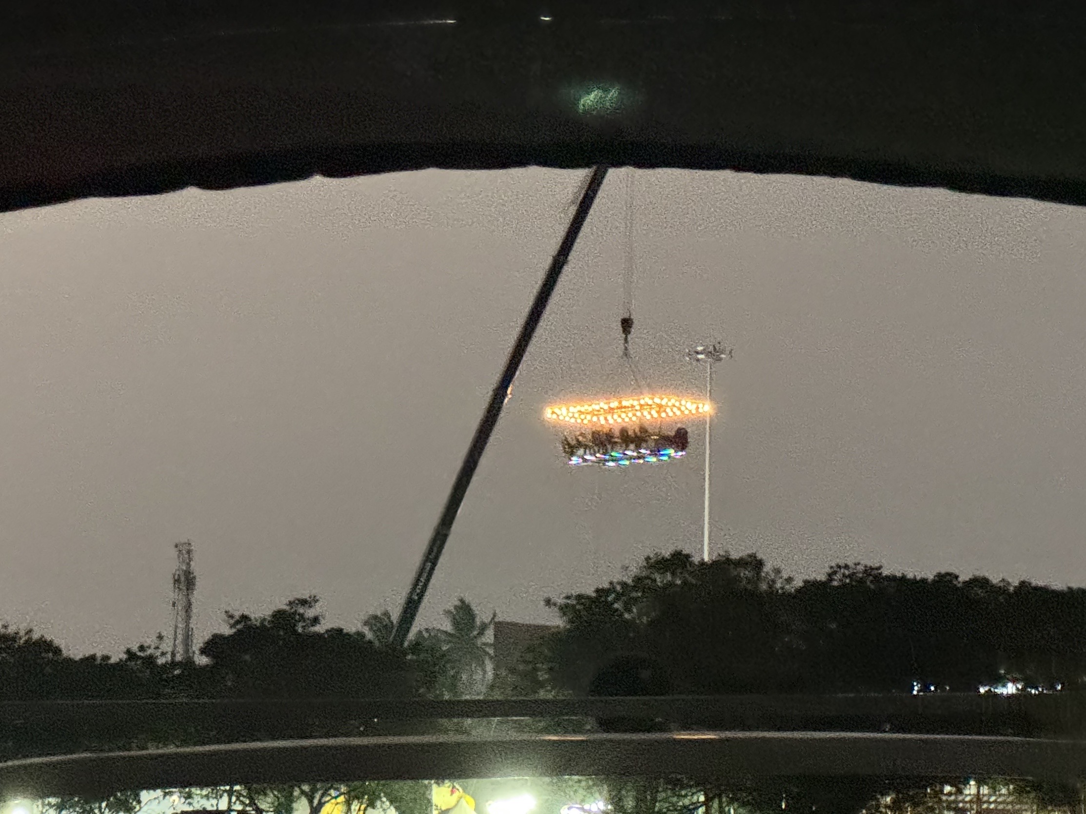 Nighttime view from inside a car during rain, windshield wipers in the foreground and blurred orange streetlights in the distance.
