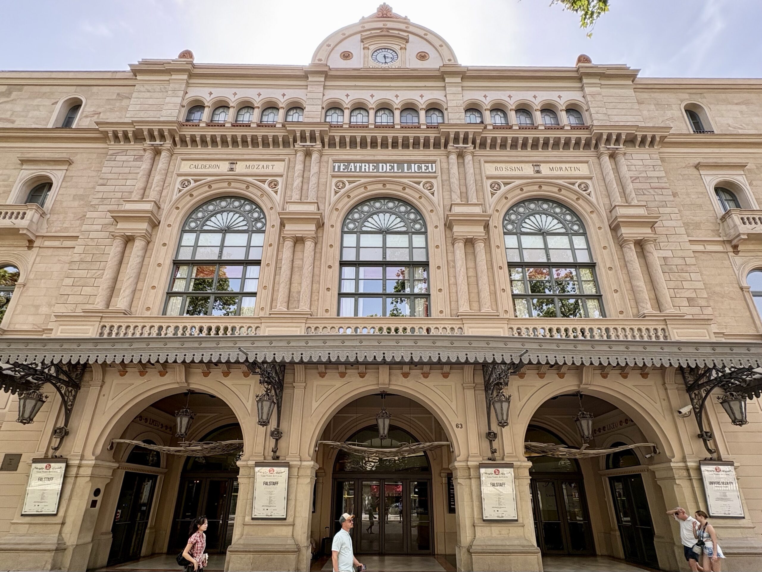 Facade of Teatre del Liceu theater with three large arched windows and decorative stonework.