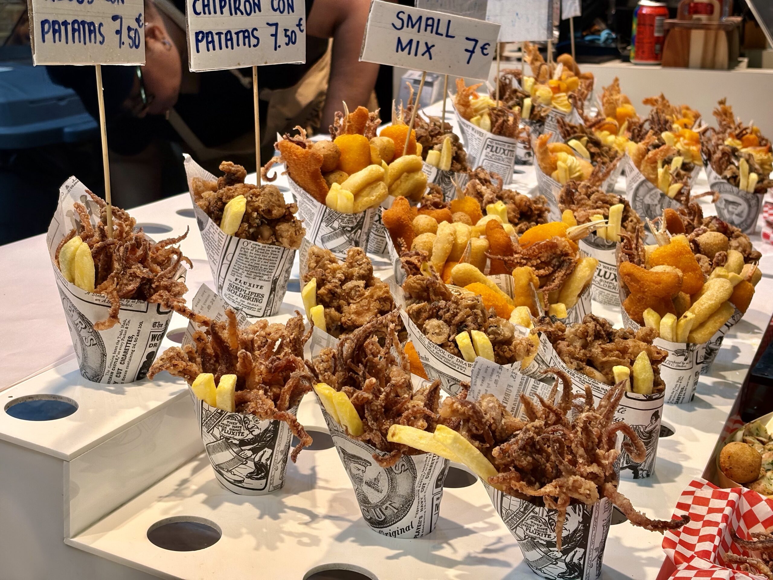 Assorted fried snacks served in newspaper cones at a street-food stall.