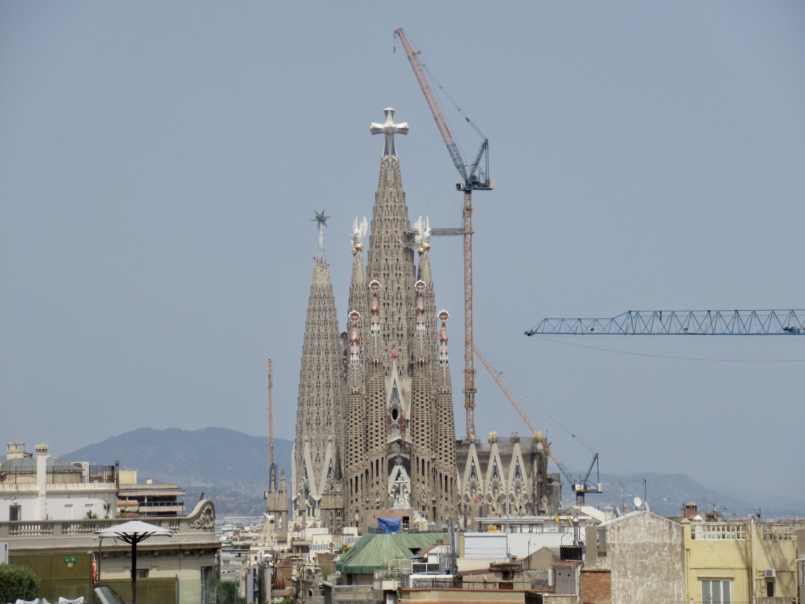 Sagrada Família basilica in Barcelona under construction with a tall spire and a crane nearby.