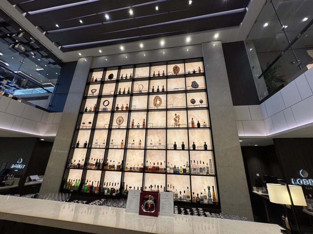 Tall illuminated liquor shelves form a grid wall in a sleek, modern bar area.