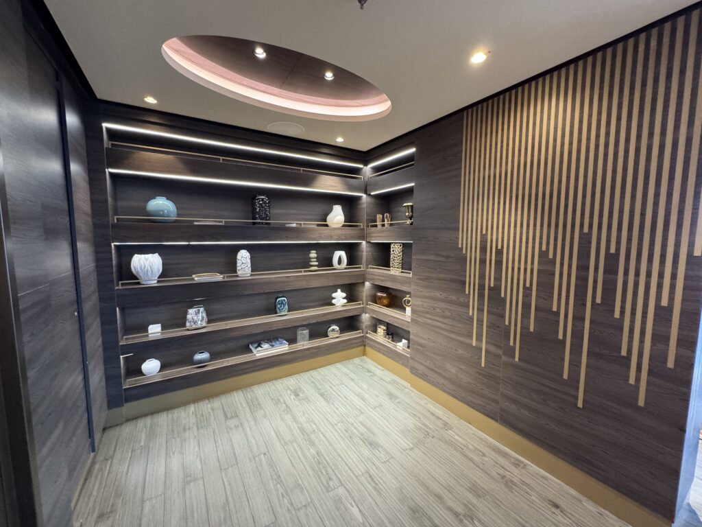 Modern display room with dark wood shelves and ceramic vases arranged on open shelves under recessed lighting, circular ceiling cutout above.