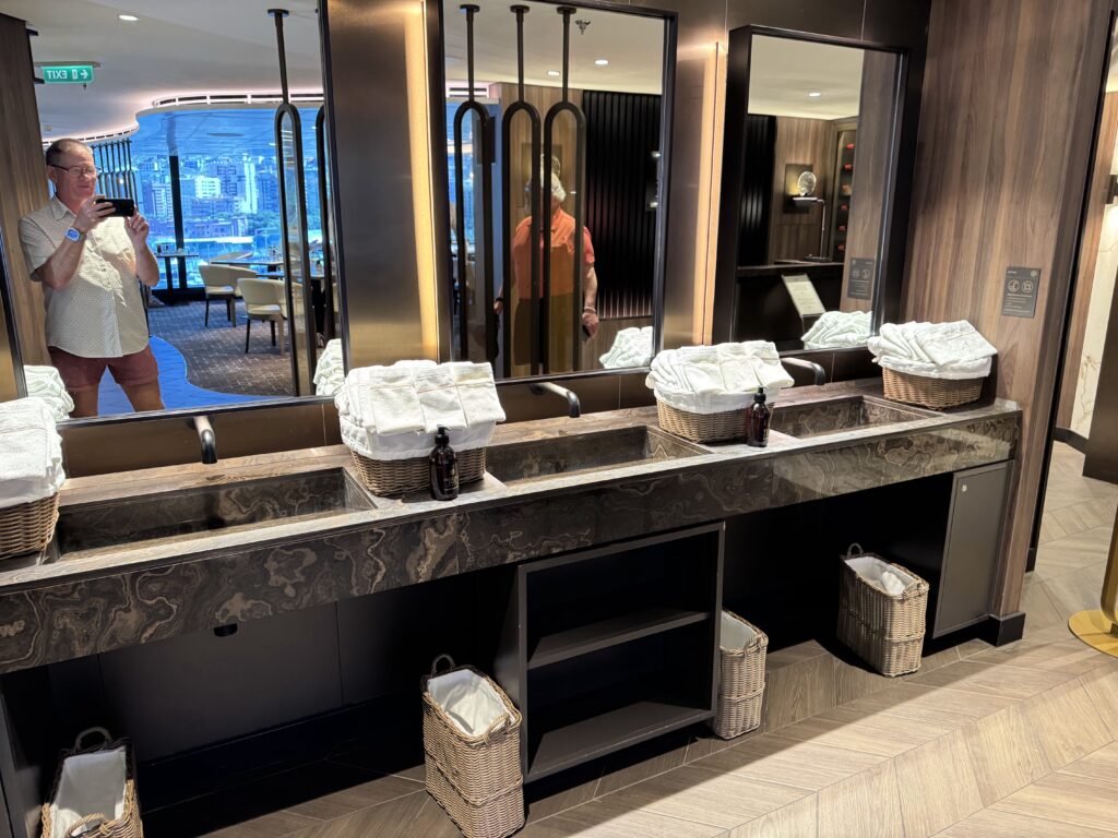 Upscale hotel bathroom vanity with black marble countertop, towels in wicker baskets, and mirrors reflecting a city view.