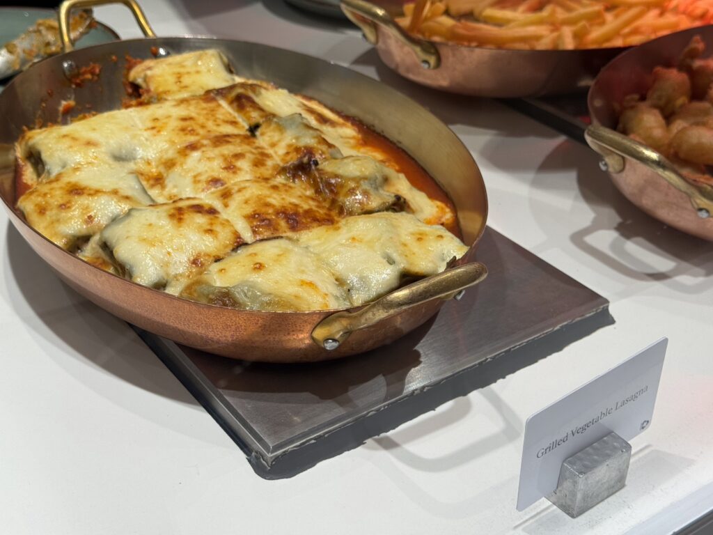 Baked lasagna with melted cheese in a copper pan at a buffet table