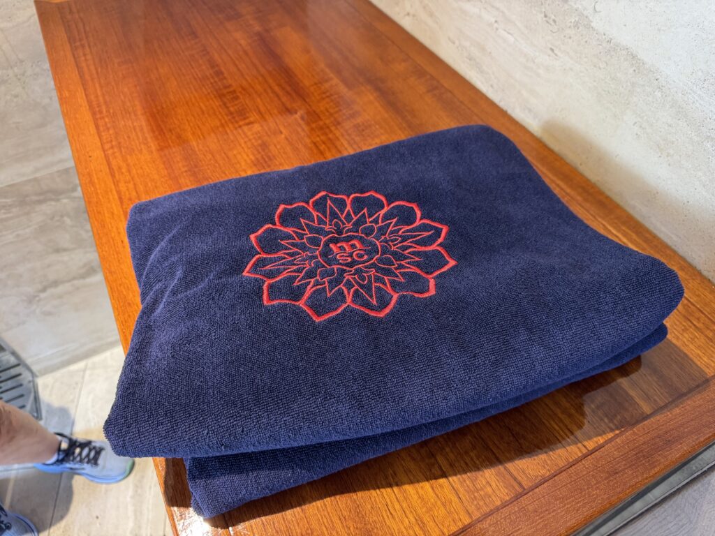 Navy towel with red embroidered flower motif folded on a wooden table surface.