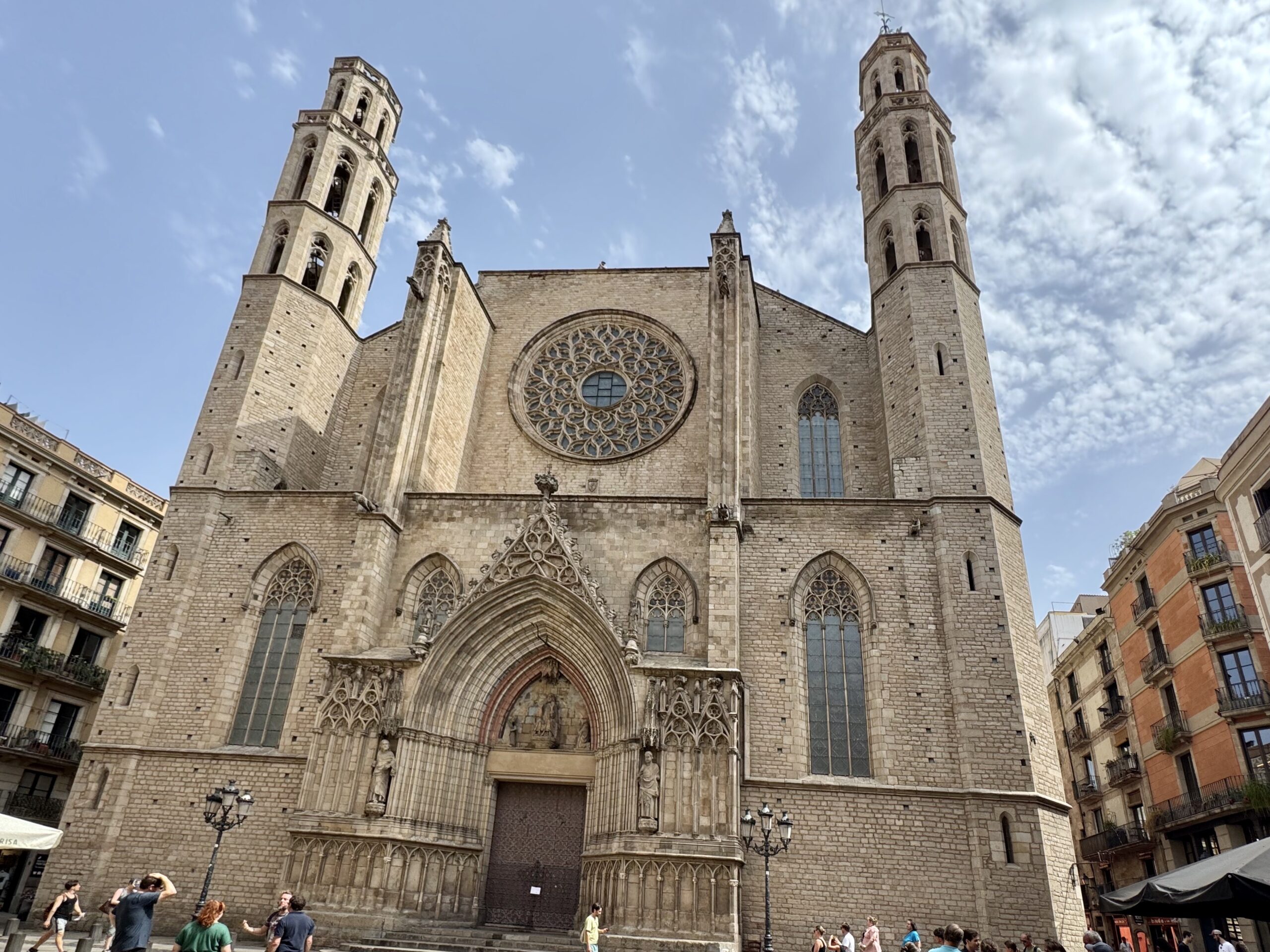 Facade of a historic cathedral with a rose window and twin towers against a blue sky.",