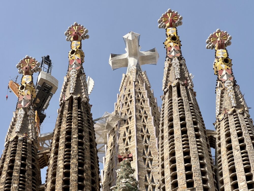 Sagrada Família tower spires with ornate mosaic details against a clear blue sky.