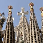 Sagrada Família tower spires with ornate mosaic details against a clear blue sky.