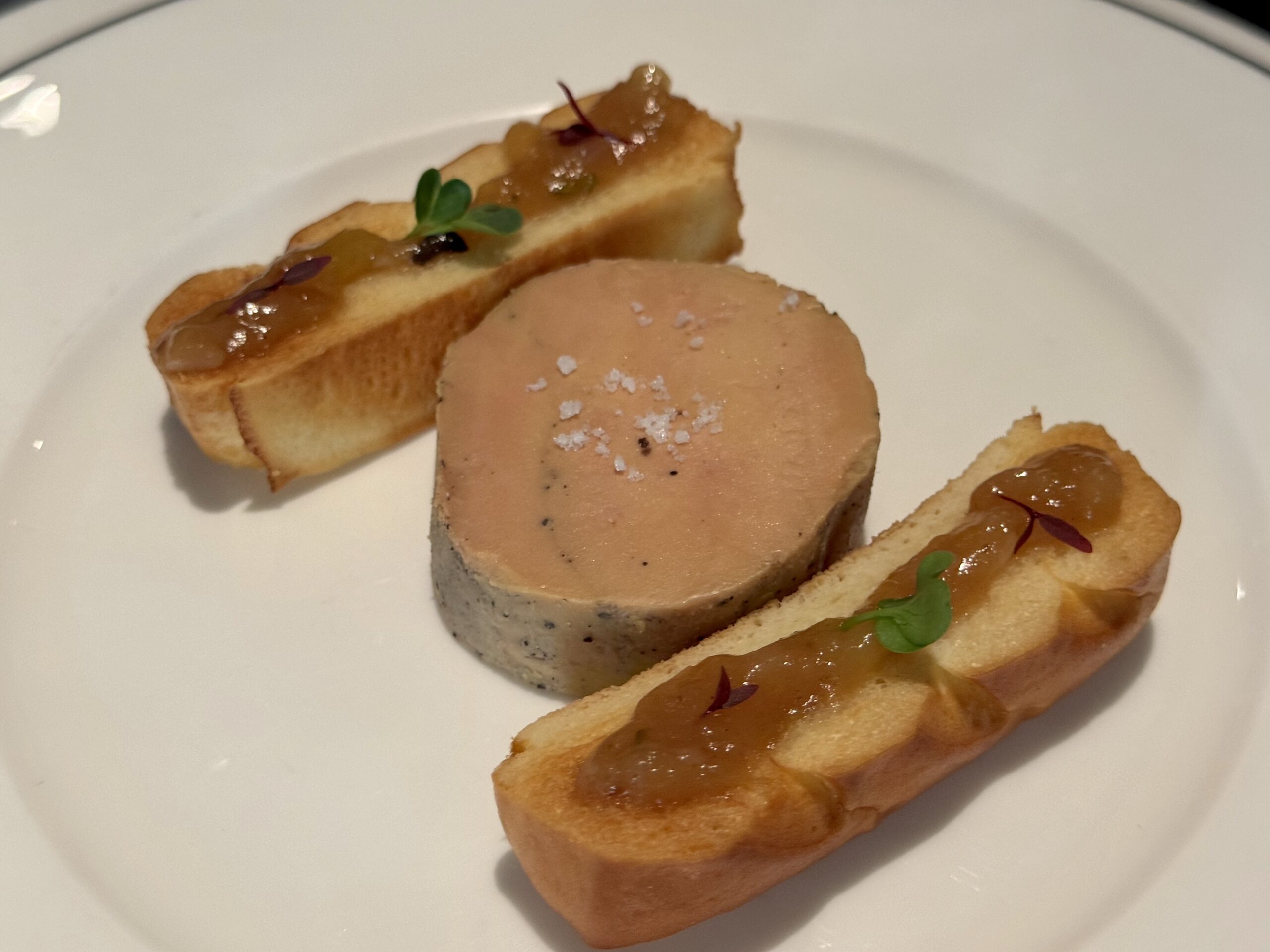 Canapés: toasted bread slices with pâté, onion chutney, and microgreens on a white plate