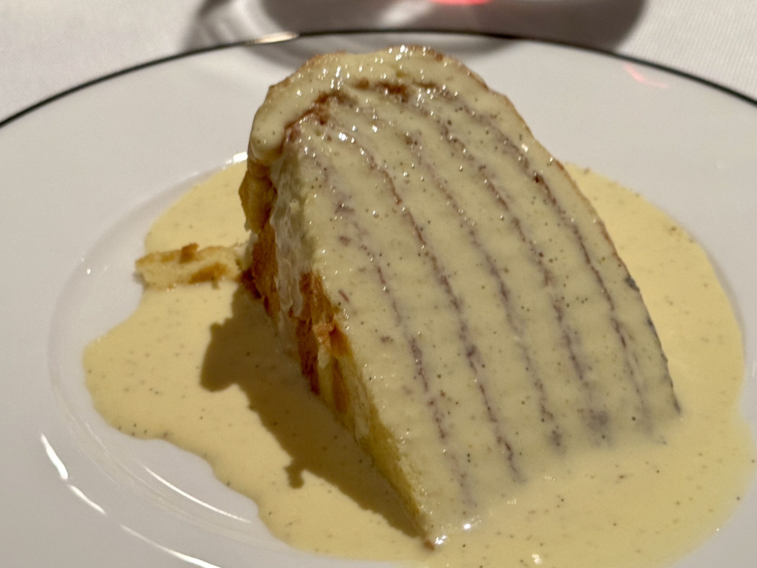 Grilled chicken breast covered in a pale creamy herb sauce on a white plate