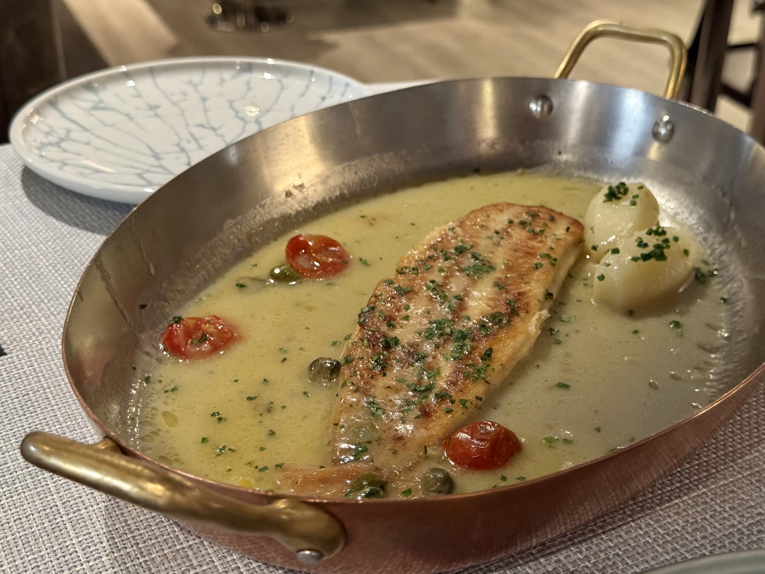Pan of creamy herb chicken with cherry tomatoes and potatoes in a skillet, garnished with chopped parsley.