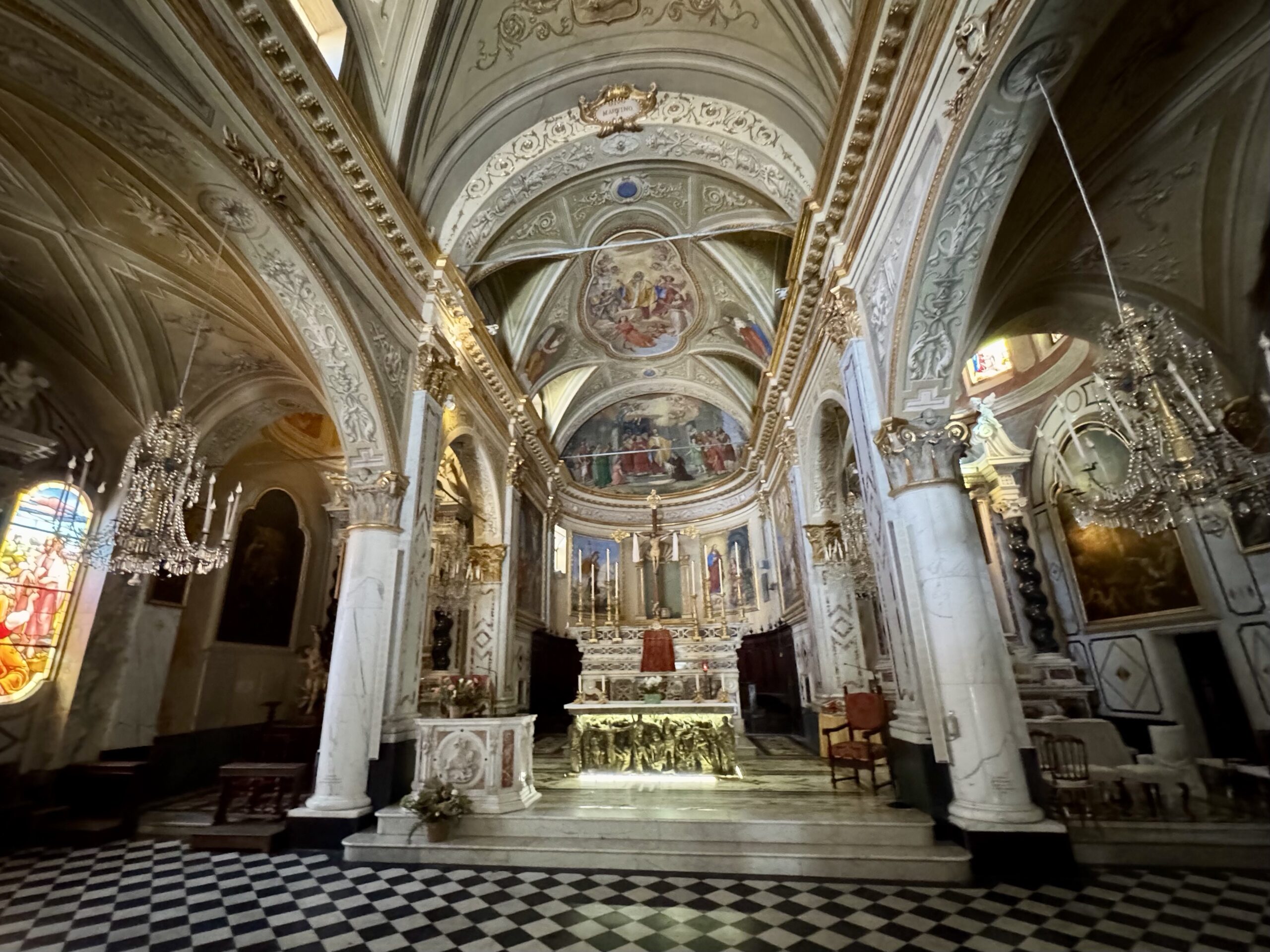 Interior of a richly decorated church with gilded arches, frescoed ceilings, and an ornate altar at the front