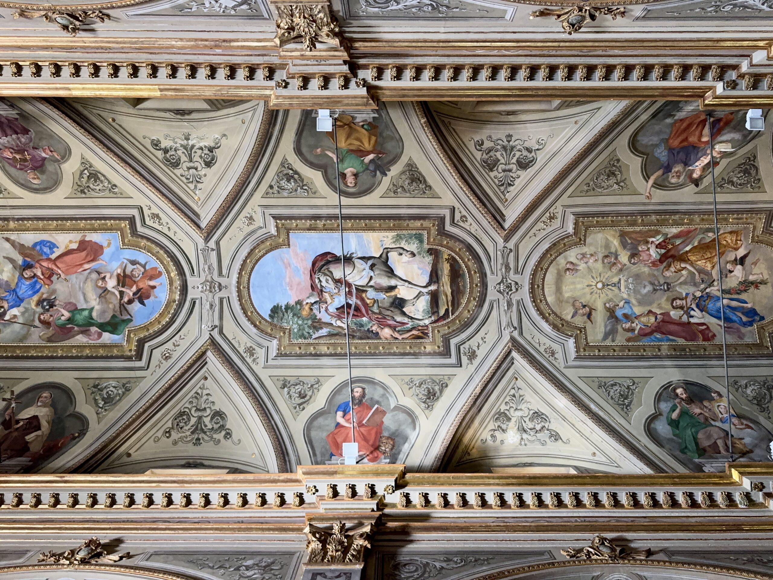 Ornate ceiling with fresco panels and gold decorative molding in a grand historic room