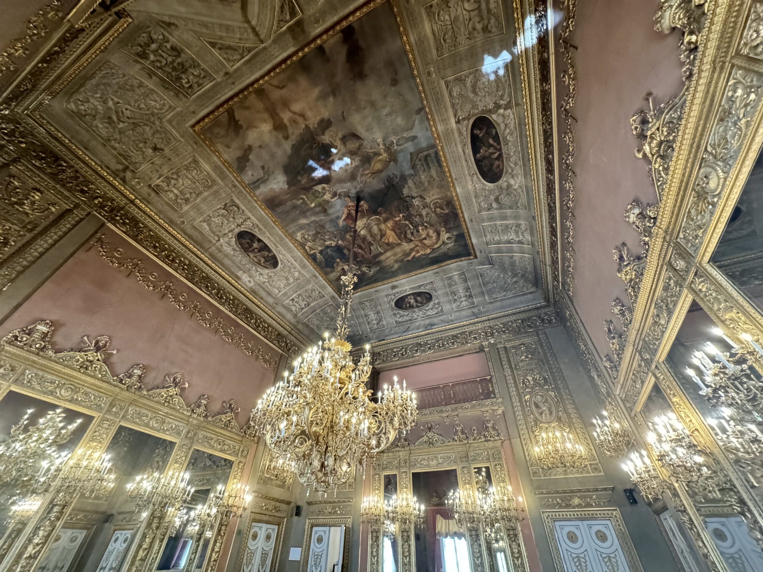 Luxuriously gilded church interior with ornate ceiling panels and a large crystal chandelier.