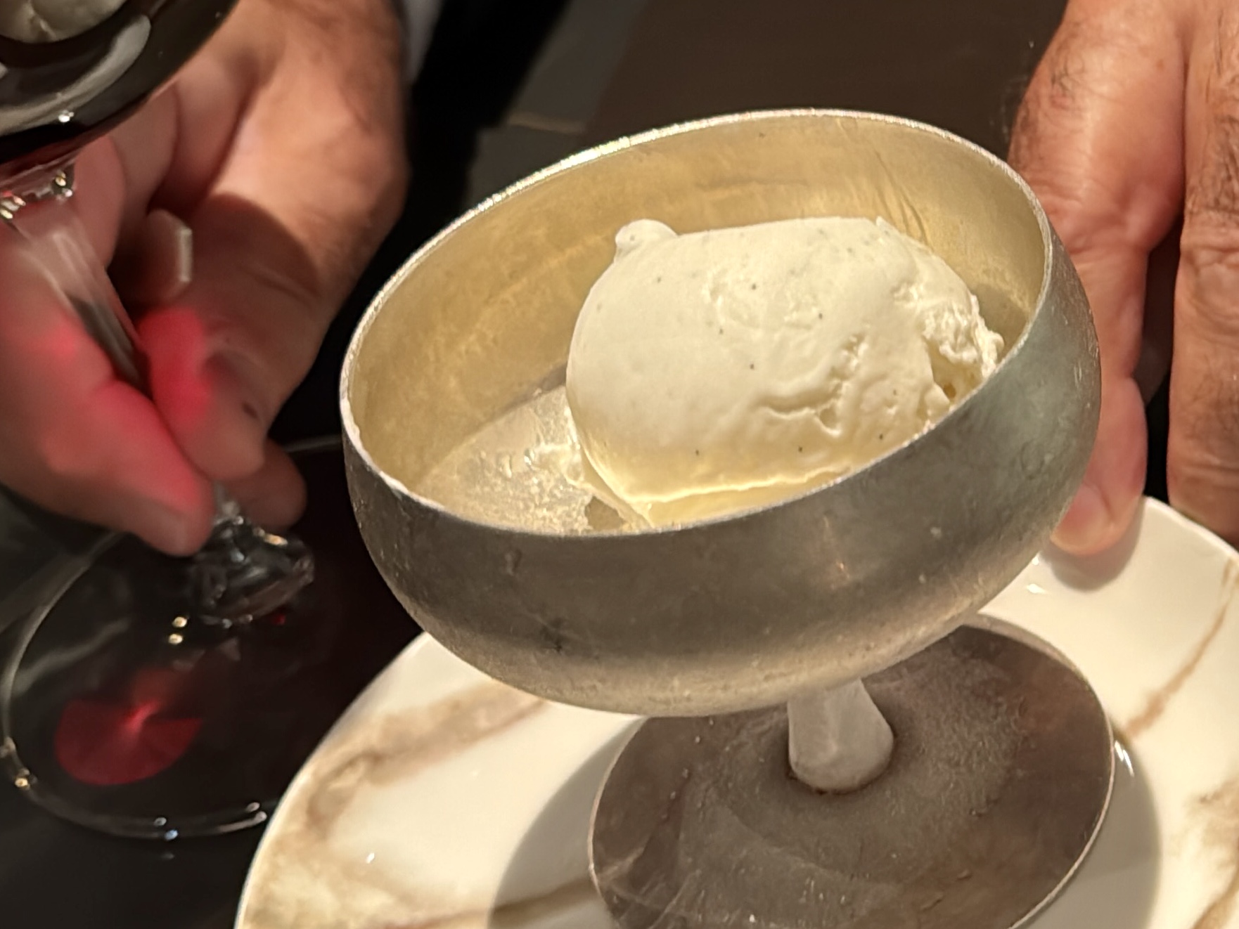 Scoop of vanilla ice cream resting in a metal ring mold over a plate, ready to serve.